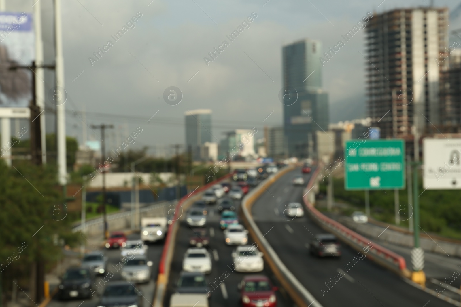 Photo of Blurred view of asphalt highway with cars and buildings in city