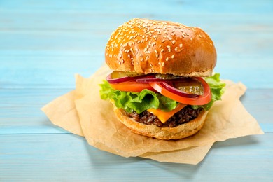 Photo of Tasty burger on light blue wooden table. Fast food