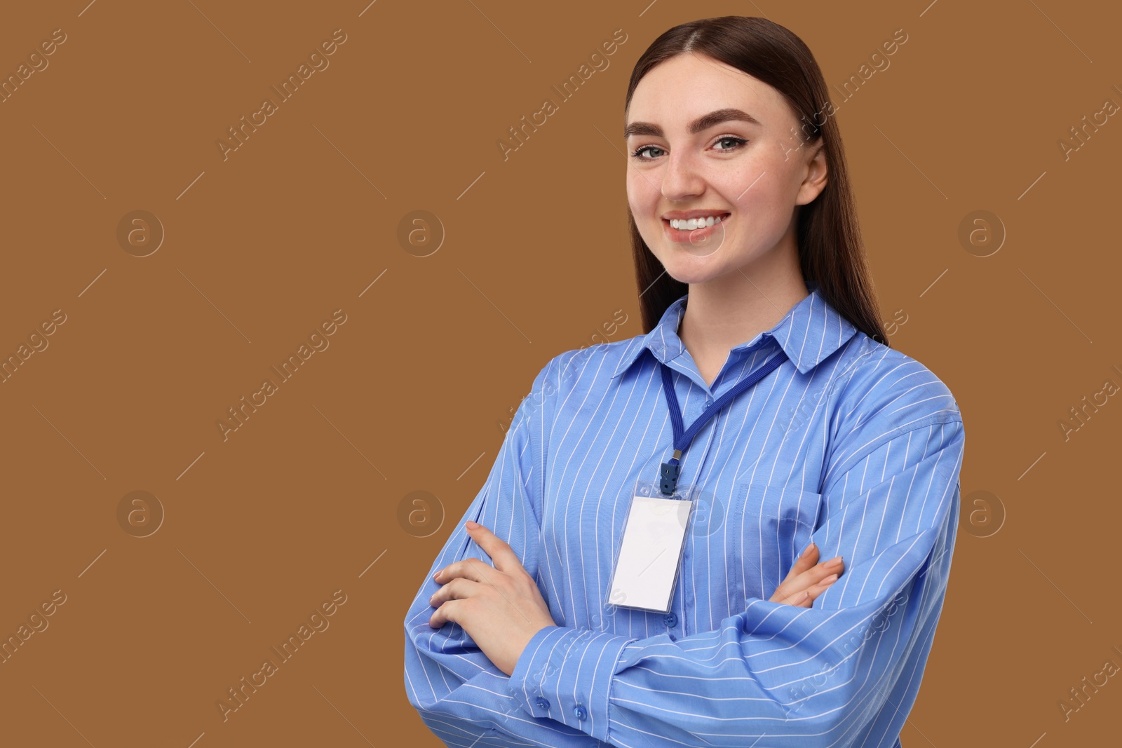 Photo of Happy woman with blank badge on brown background, space for text