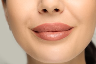 Photo of Woman with nude lipstick on light background, closeup