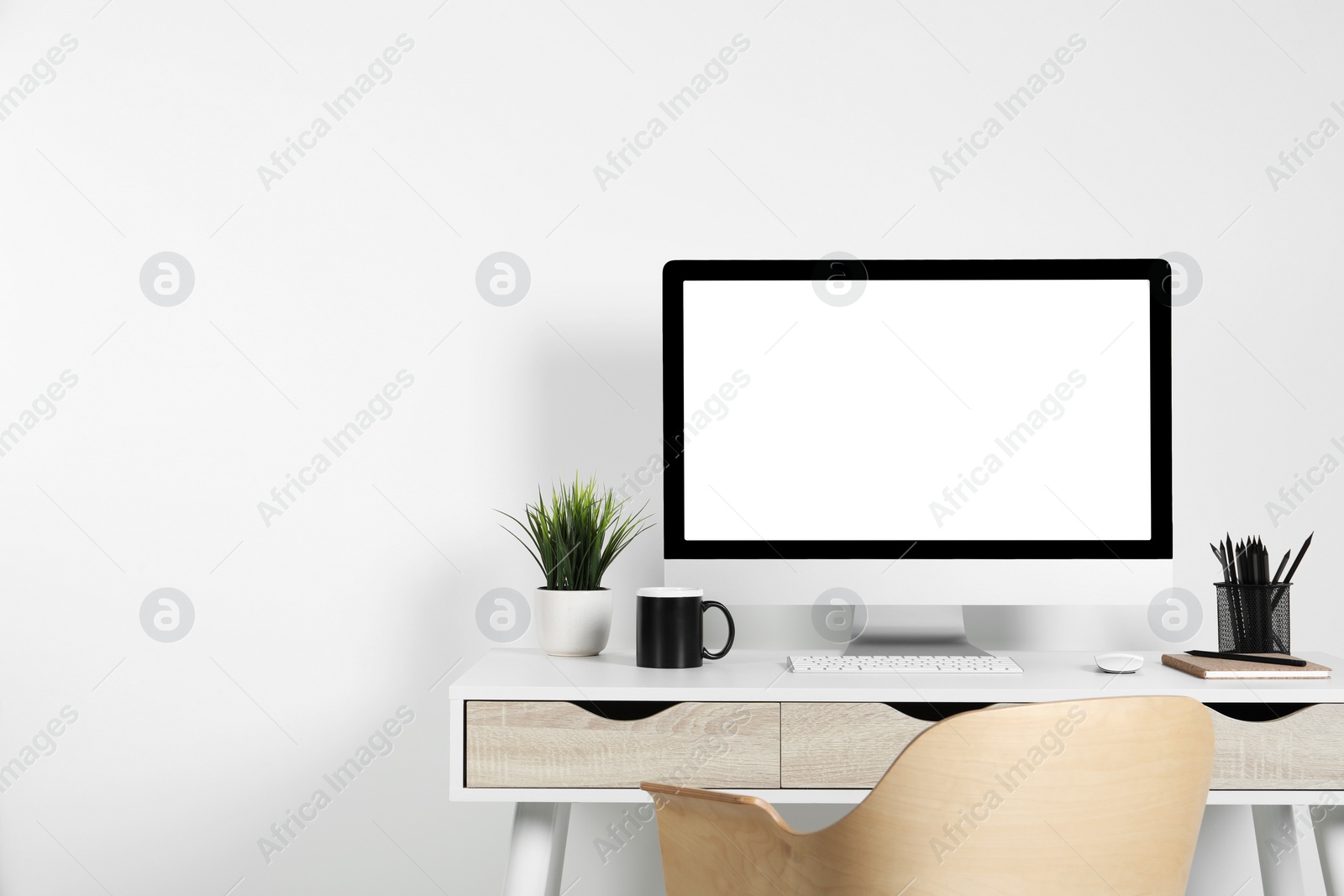 Photo of Cozy workspace with computer, houseplant and stationery on wooden desk at home