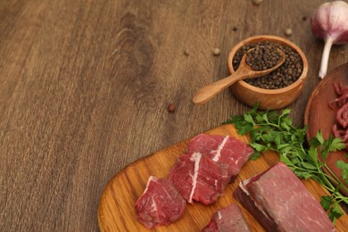 Beef, garlic, parsley and peppercorns on wooden table. Space for text