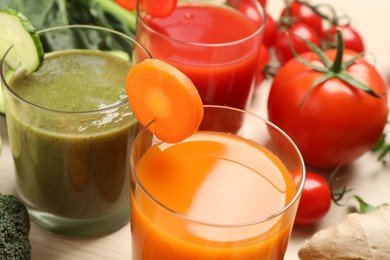 Delicious vegetable juices and fresh ingredients on wooden table, closeup