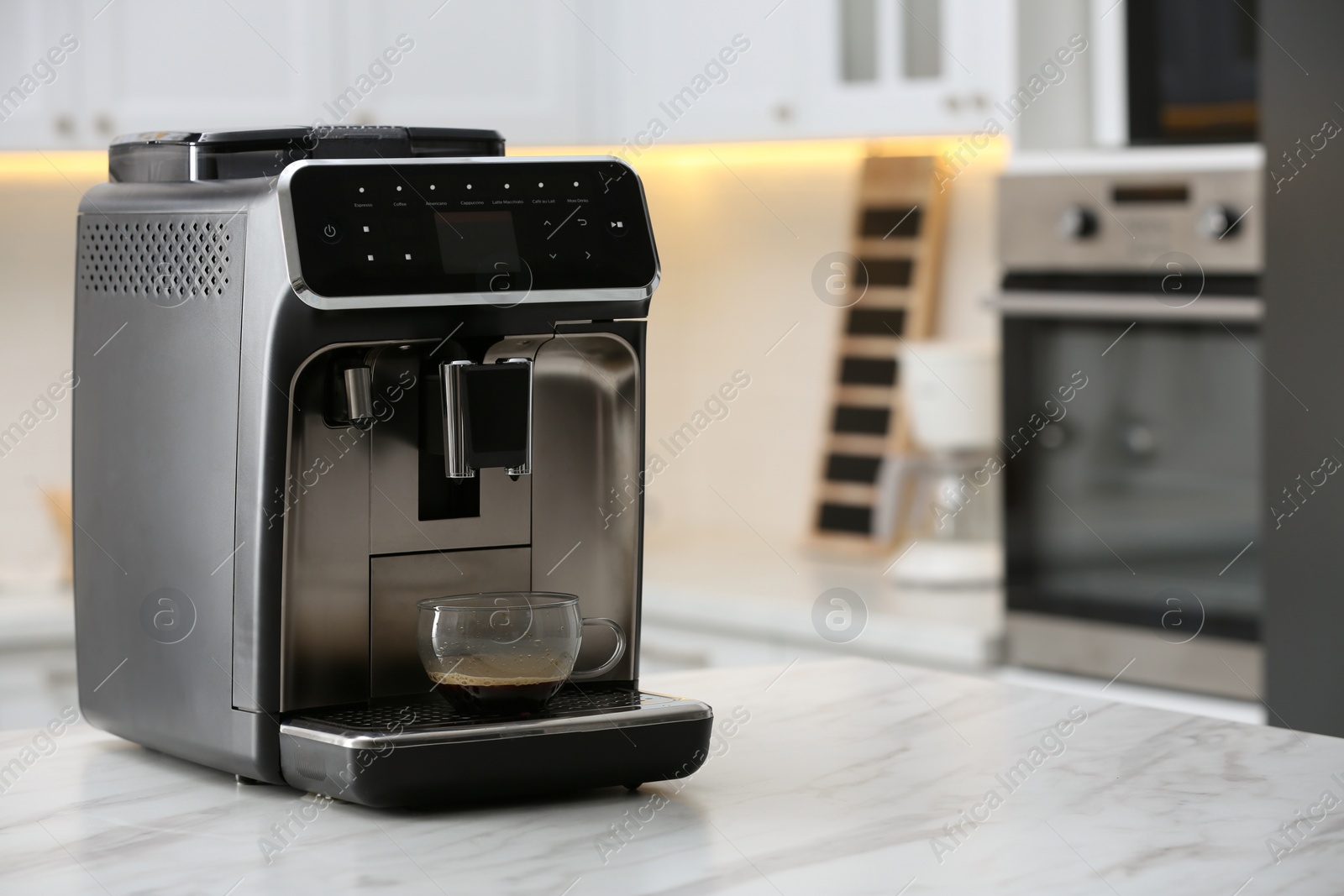 Photo of Modern electric espresso machine with glass cup of coffee on white marble countertop in kitchen