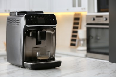 Photo of Modern electric espresso machine with glass cup of coffee on white marble countertop in kitchen