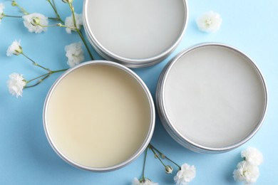 Photo of Different lip balms and gypsophila on light blue background, flat lay