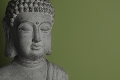 Photo of Beautiful stone Buddha sculpture on green background. Space for text