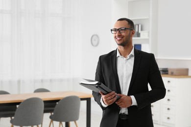 Photo of Smiling young businessman with folders in office. Space for text