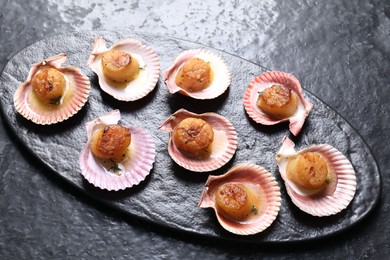 Photo of Delicious fried scallops in shells on black table