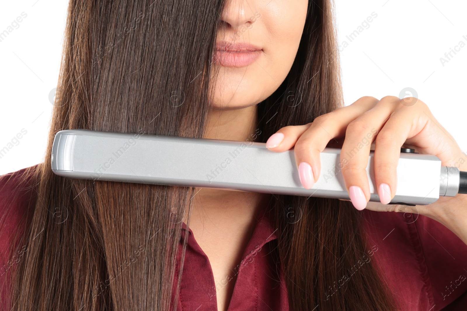 Photo of Young woman using hair iron on white background, closeup