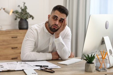 Photo of Overwhelmed man sitting at table in office