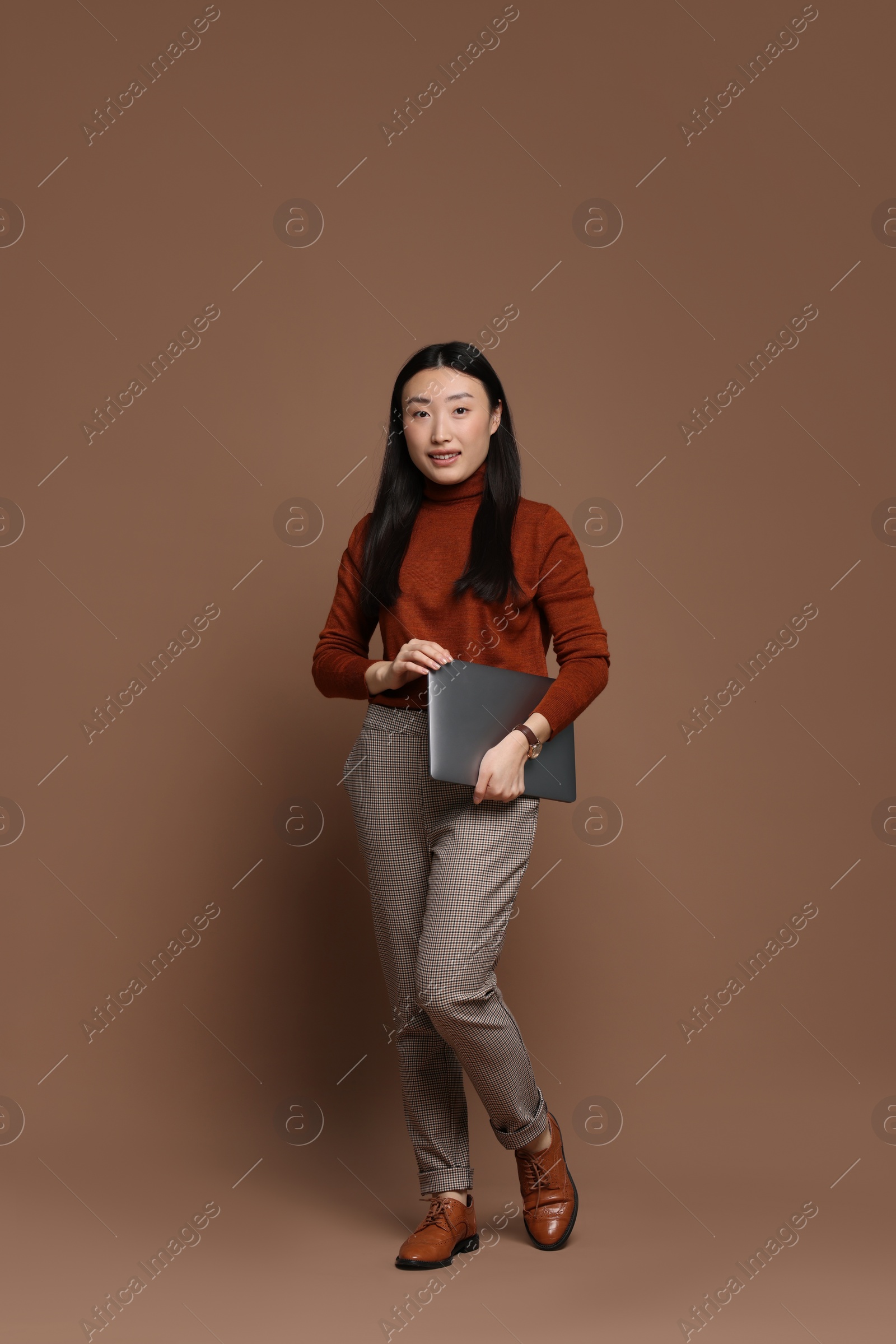 Photo of Full length portrait of smiling woman with laptop on brown background