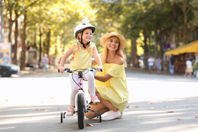 Photo of Mother teaching daughter to ride bicycle on street
