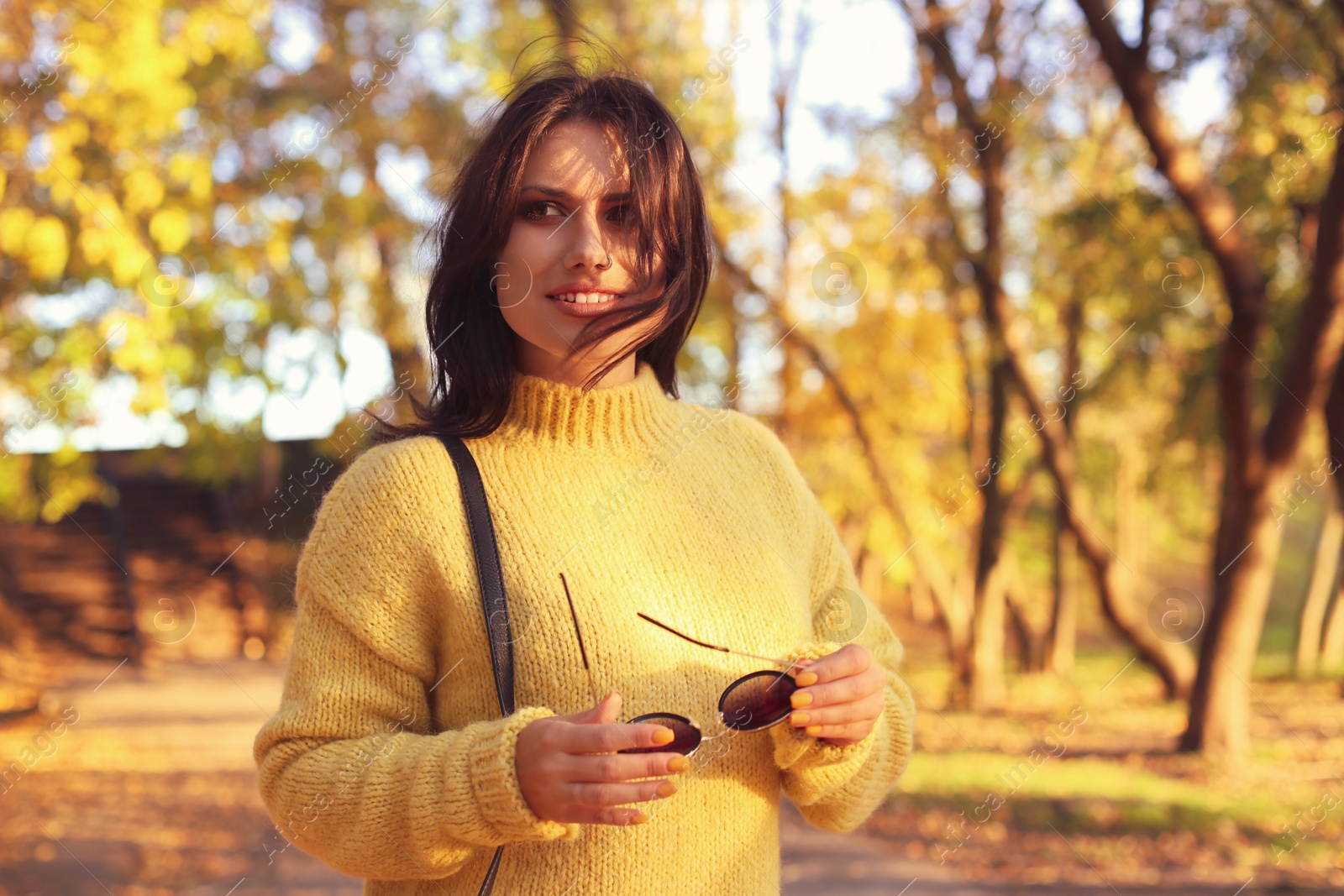 Photo of Beautiful young woman wearing stylish sweater in autumn park