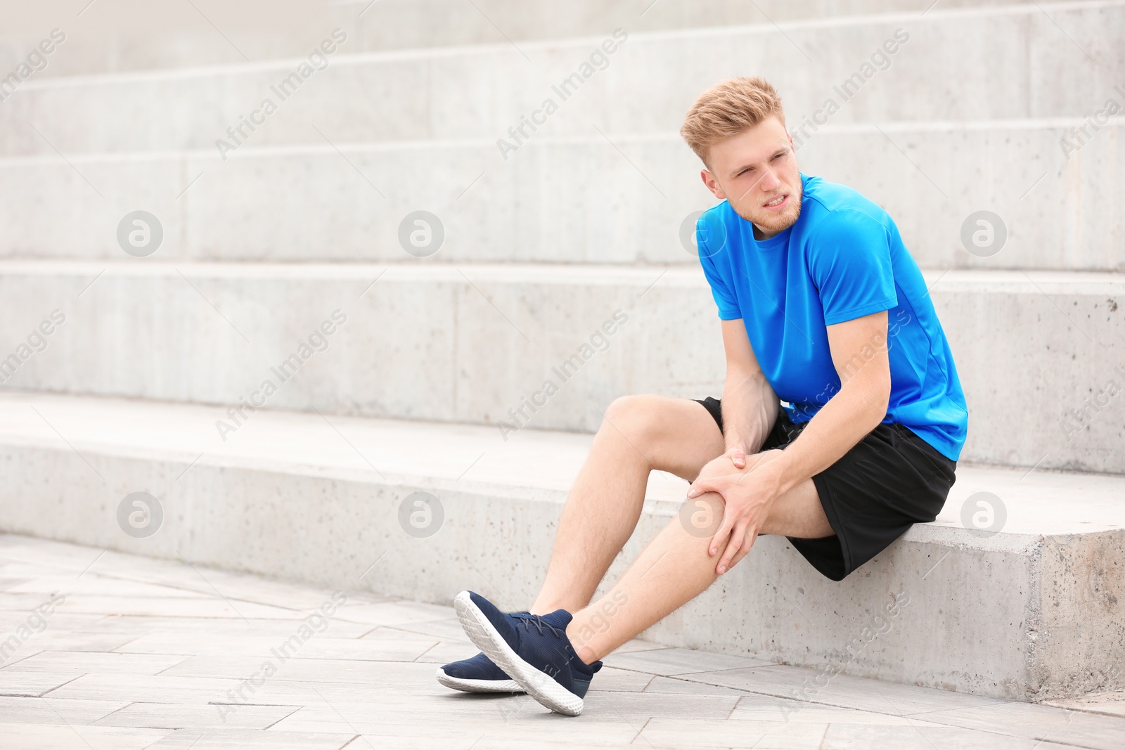 Photo of Man in sportswear suffering from knee pain on stairs