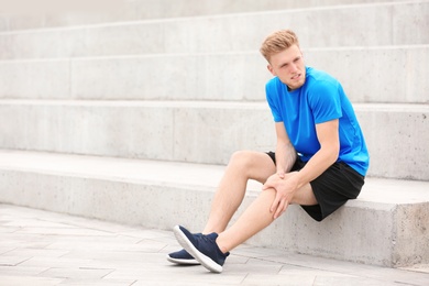 Photo of Man in sportswear suffering from knee pain on stairs