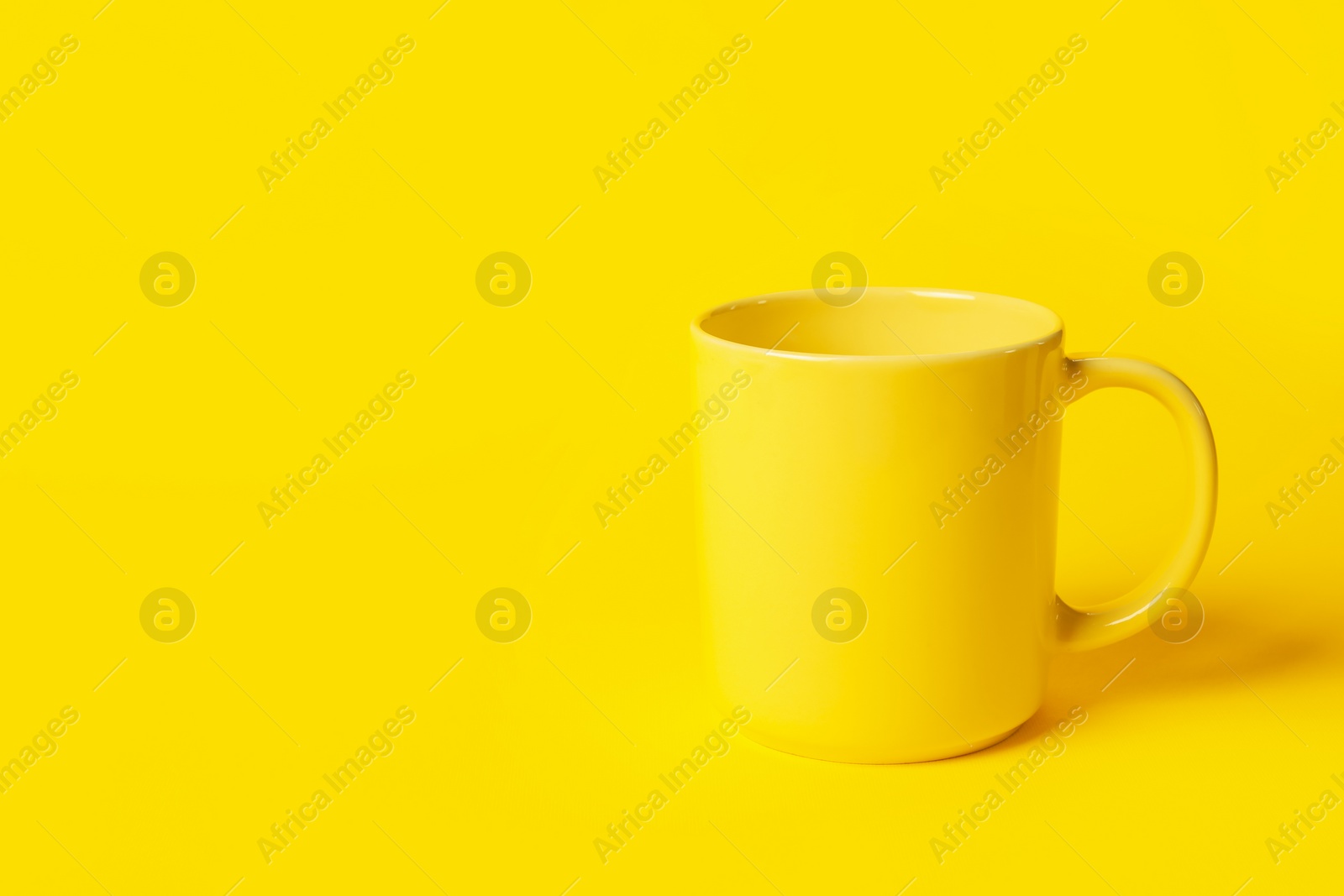 Photo of One ceramic mug on yellow background, space for text