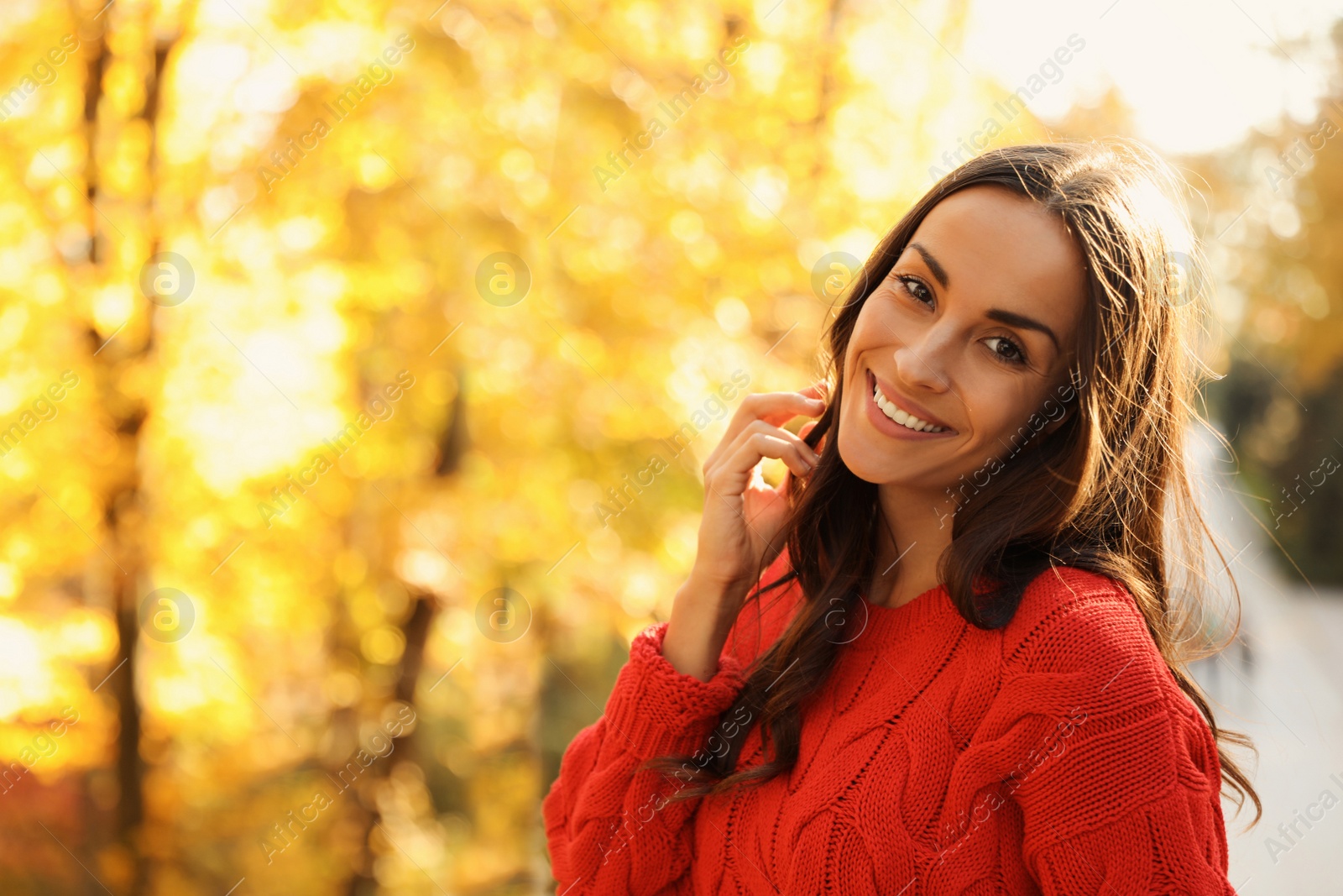 Photo of Beautiful woman wearing red sweater in sunny park. Autumn walk