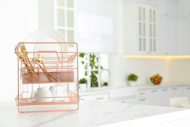 Clean dishes on drying rack in modern kitchen interior, space for text