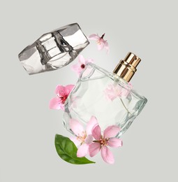 Bottle of perfume and sakura flowers in air on grey background
