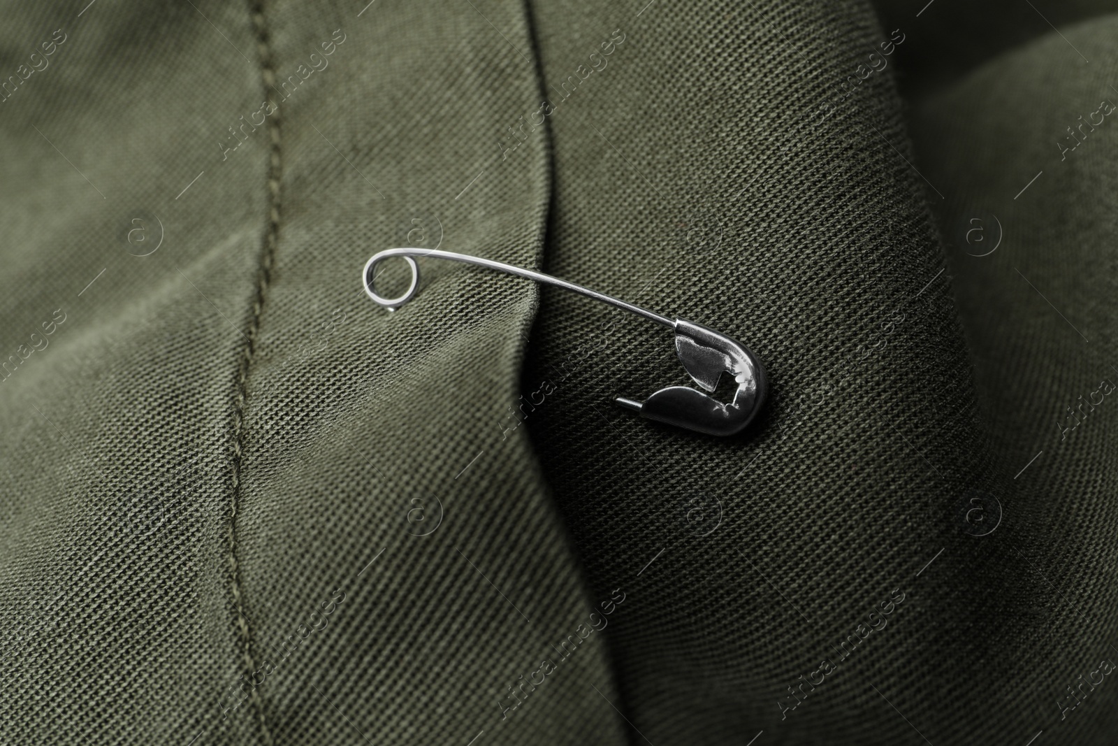 Photo of Closeup view of metal safety pin on clothing