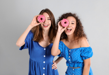 Photo of Beautiful young women with donuts on light grey background