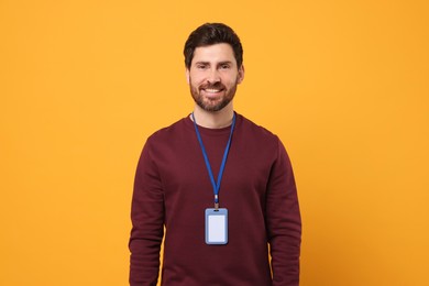 Smiling man with VIP pass badge on orange background