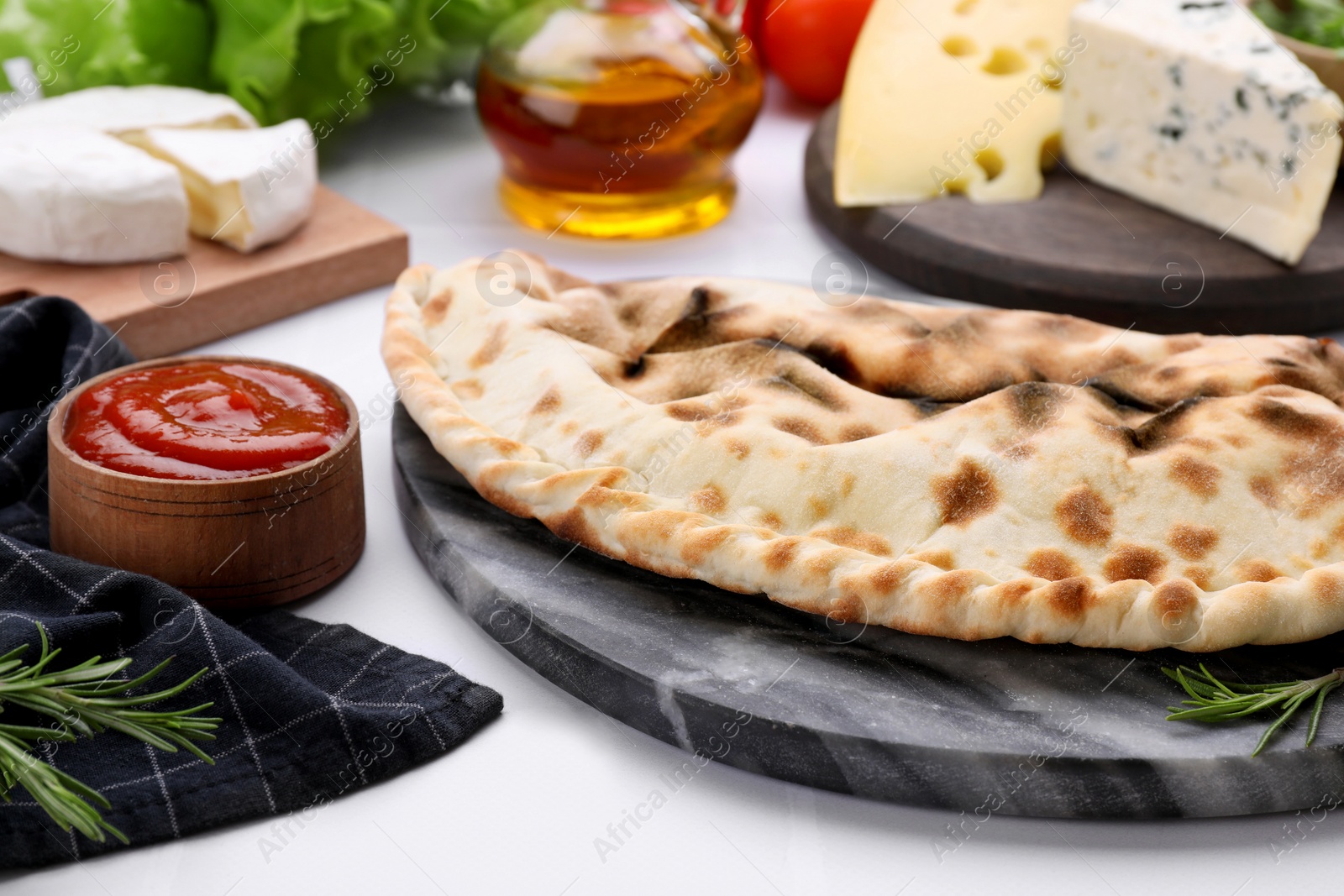 Photo of Tasty pizza calzone with tomato sauce and different products on white table