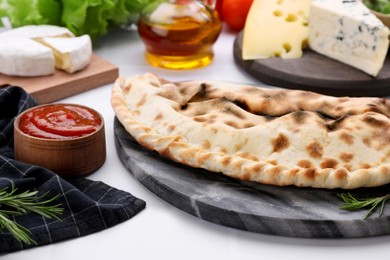 Tasty pizza calzone with tomato sauce and different products on white table