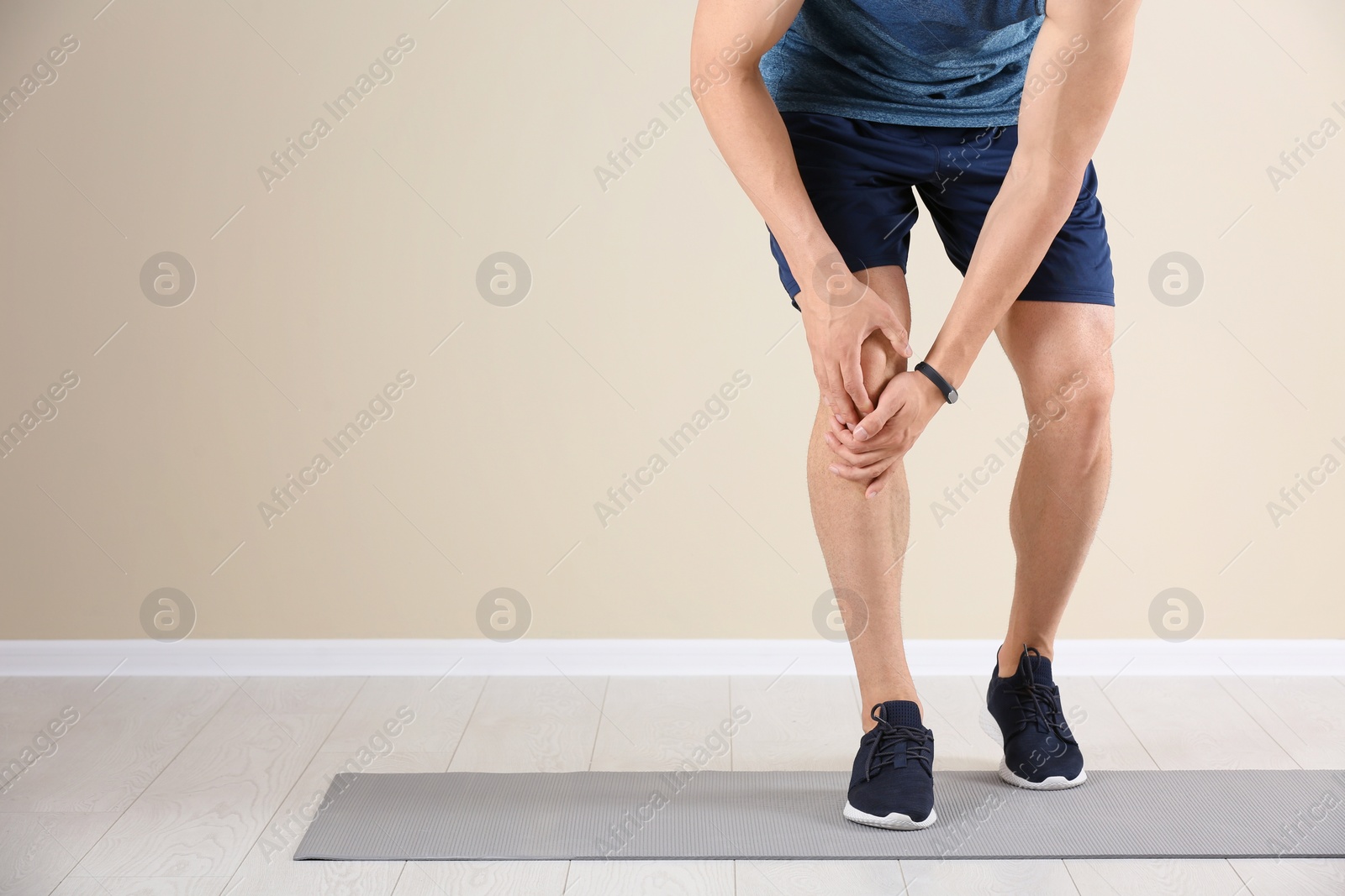 Photo of Male athlete suffering from knee pain during training indoors