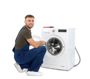 Plumber fixing washing machine on white background