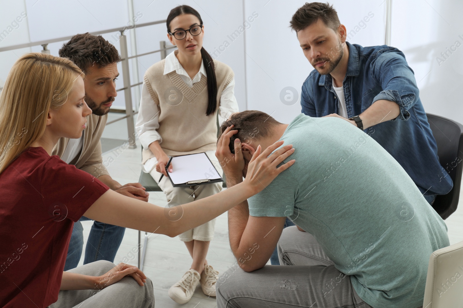 Photo of Psychotherapist working with group of drug addicted people at therapy session indoors