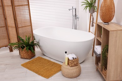 Photo of Stylish bathroom interior with soft bath mat and tub