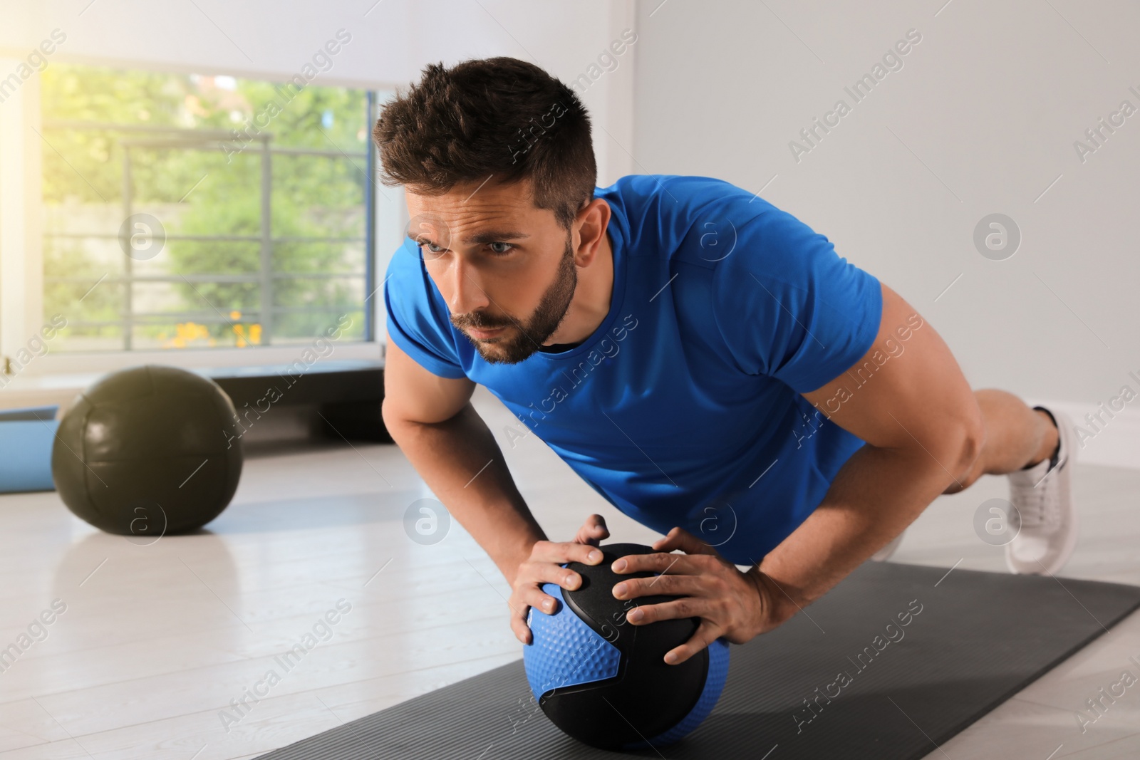 Photo of Athletic man doing push ups with medicine ball in modern gym