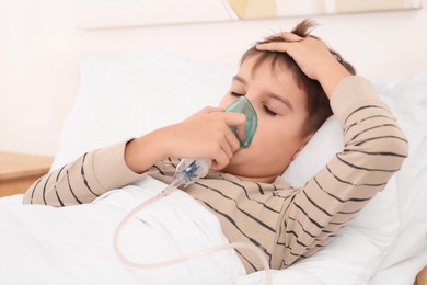 Boy using nebulizer for inhalation on bed at home