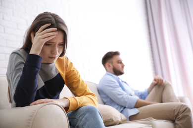 Photo of Unhappy couple with problems in relationship at home, focus on woman