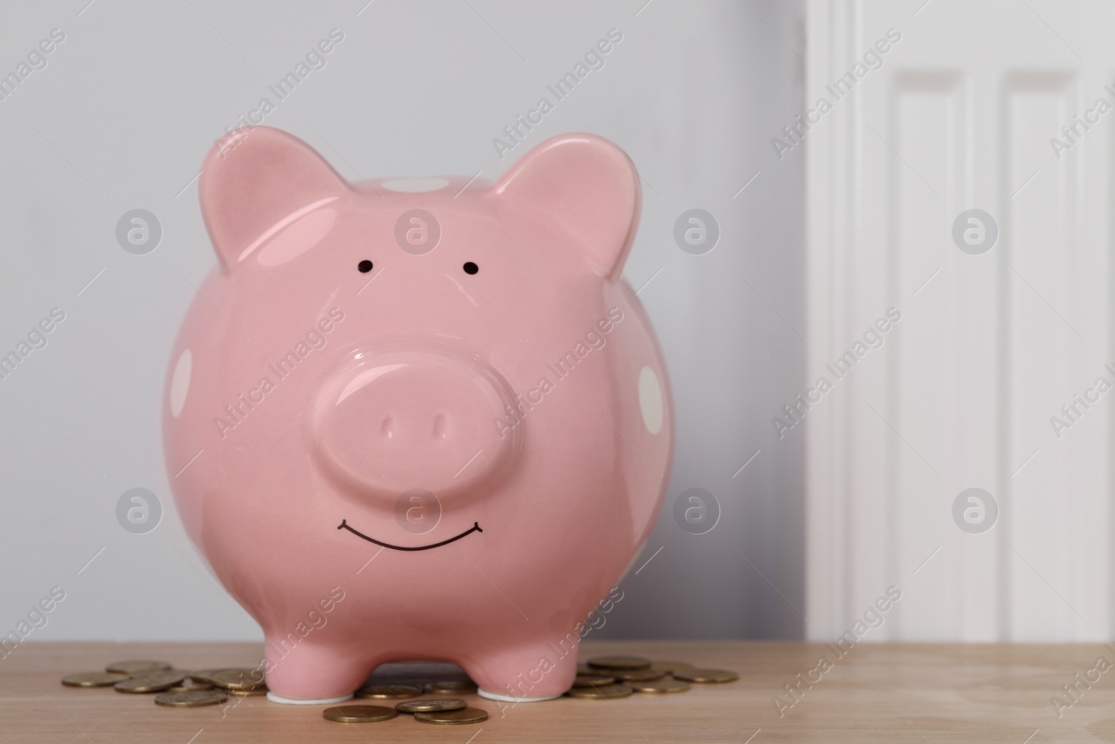 Photo of Piggy bank and coins on wooden table near heating radiator, space for text