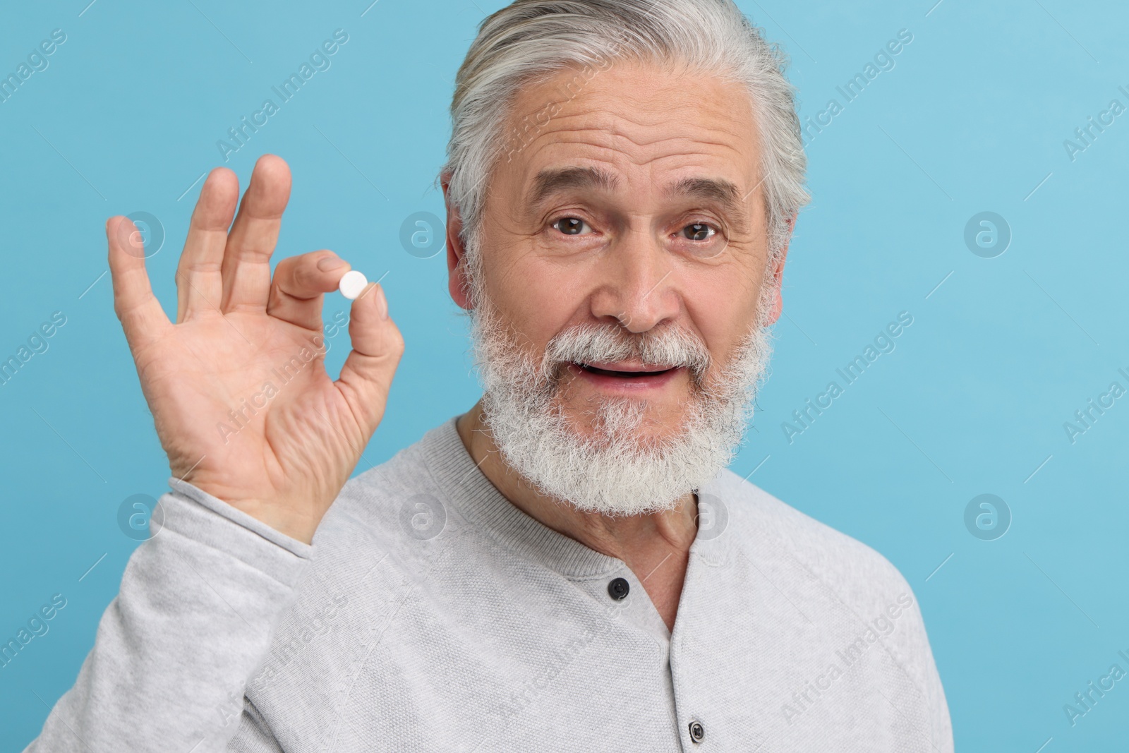 Photo of Senior man with pill on light blue background