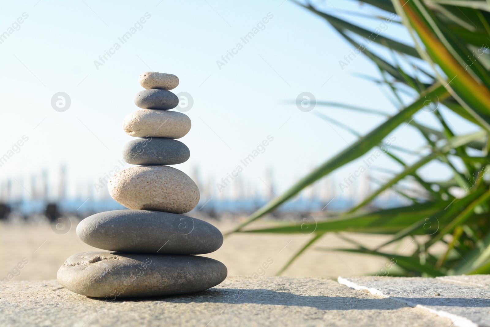 Photo of Stack of stones on parapet near sea, space for text