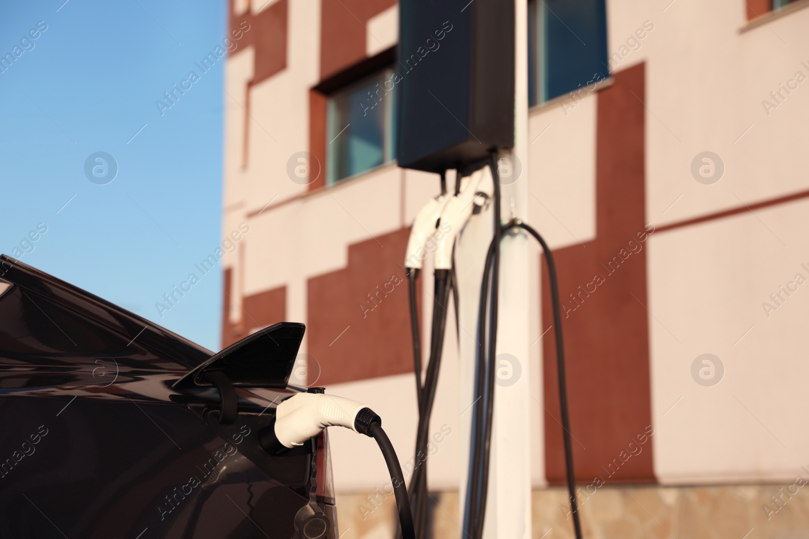 Photo of Charging modern electric car from station outdoors