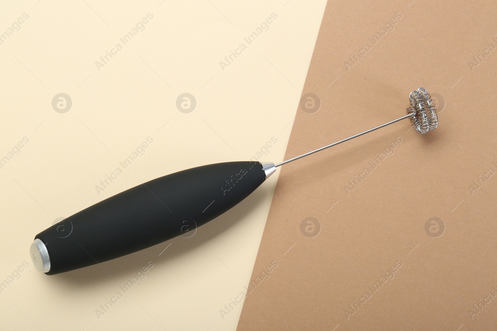 Photo of Black milk frother wand on color background, top view