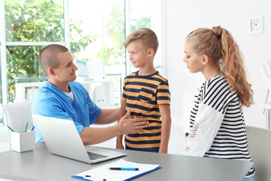 Male medical assistant consulting mother with son in clinic