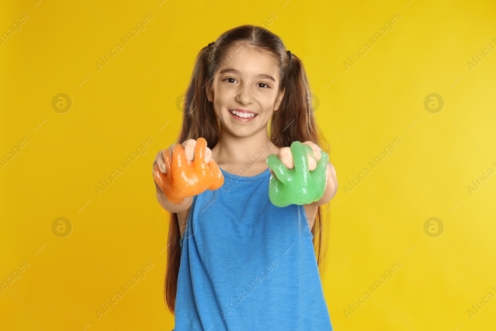 Photo of Preteen girl with slime on yellow background