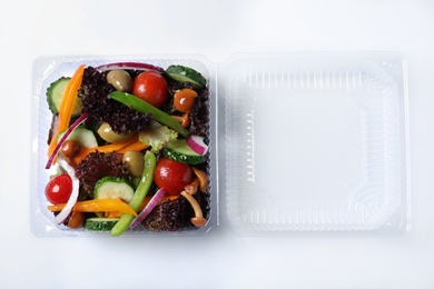 Plastic container with fresh salad on white background, top view