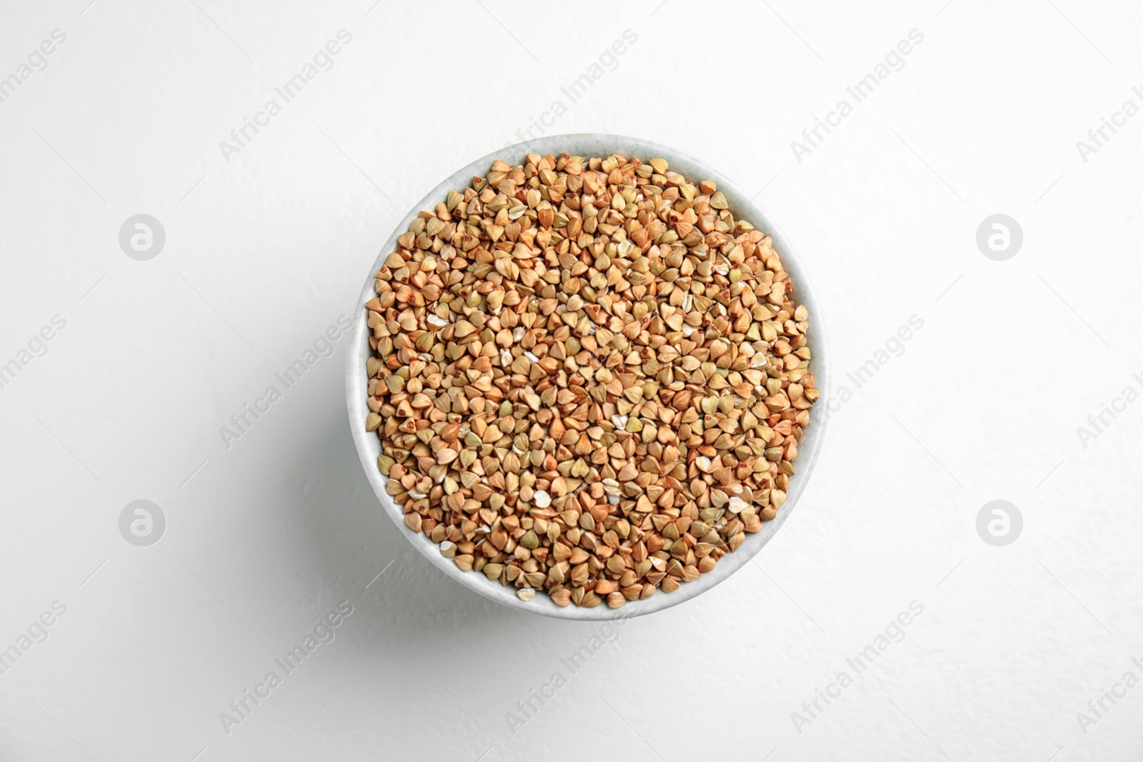 Photo of Bowl with green buckwheat on white table, top view