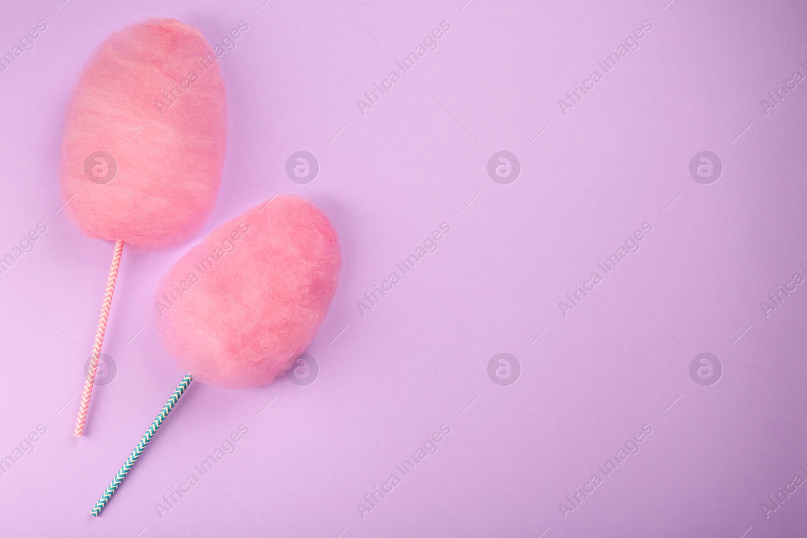 Photo of Two sweet pink cotton candies on lilac background, flat lay. Space for text