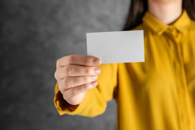 Photo of Woman holding blank business card on grey background, closeup. Mockup for design