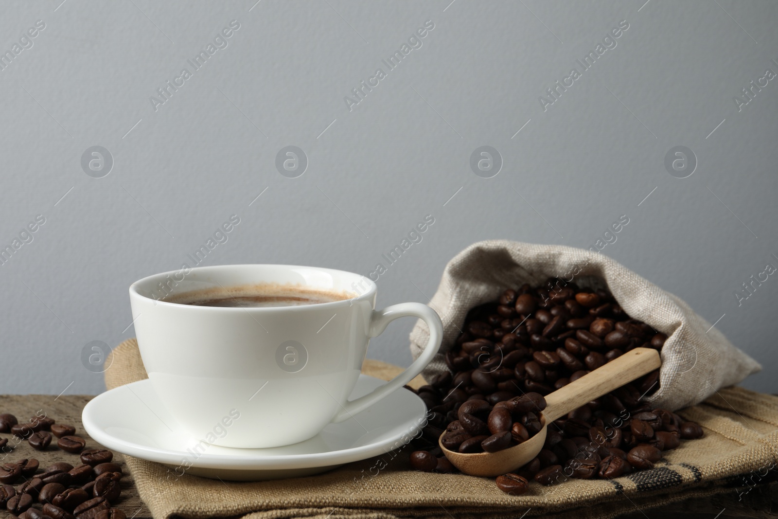 Photo of Cup of aromatic coffee and beans on wooden table