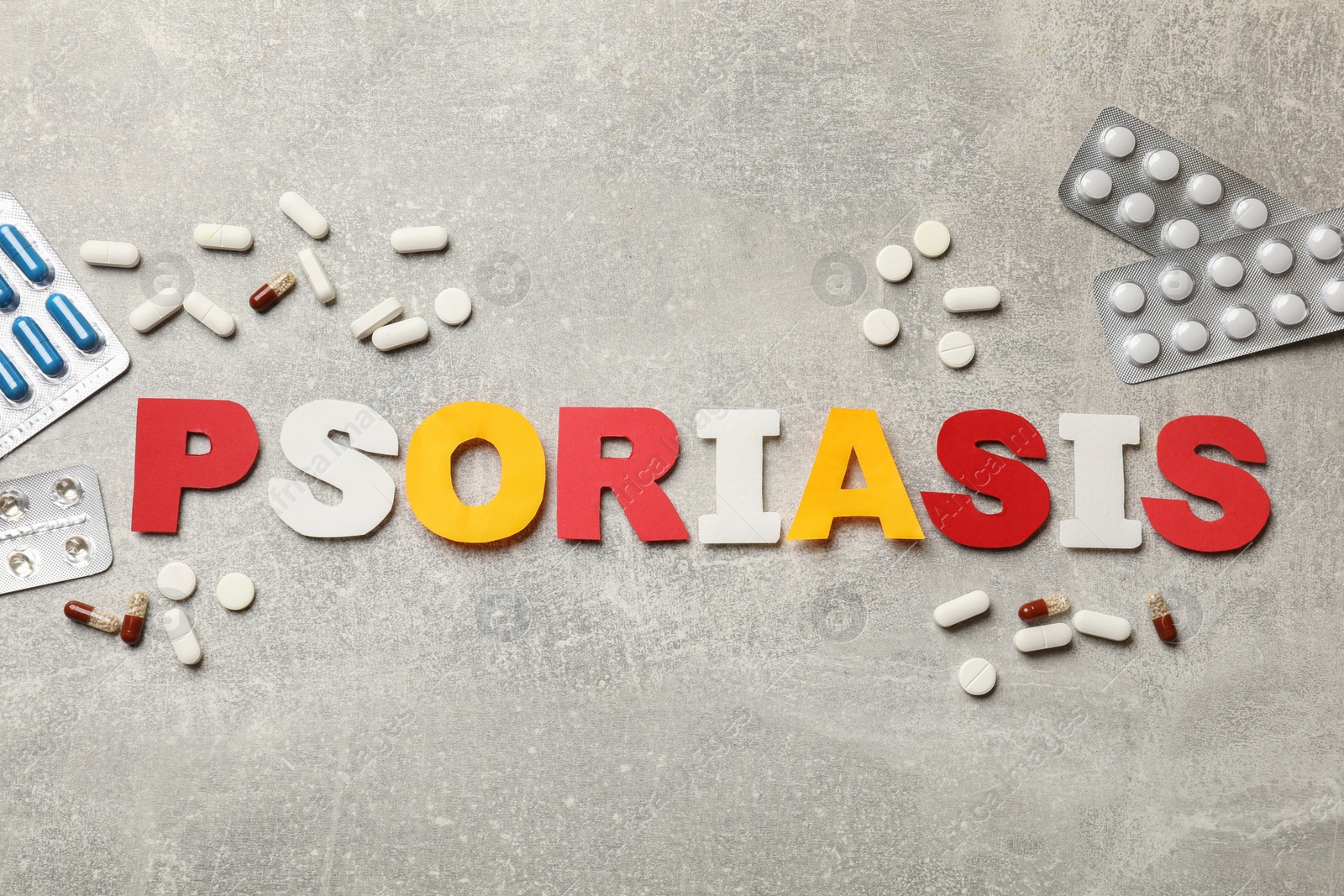 Photo of Word Psoriasis made of paper letters and pills on light gray textured table, flat lay