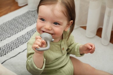 Cute baby girl with nibbler on floor at home